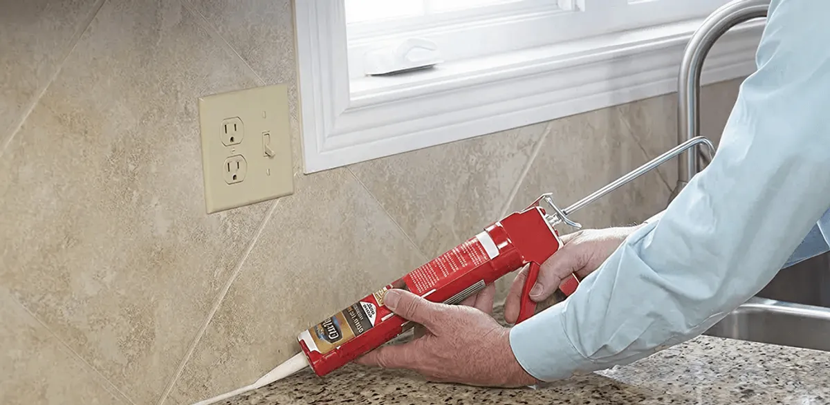 Handyman applying caulk along a kitchen backsplash and countertop seam in Fort Worth, TX