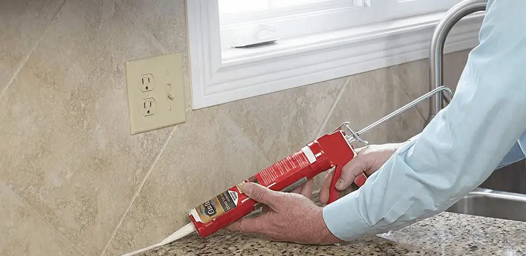 Handyman applying caulk along a kitchen backsplash and countertop seam in Fort Worth, TX