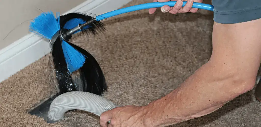 Dryer vent cleaning technician brushing lint from a vent line in Fort Worth, TX