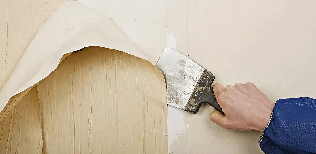 Handyman removing wallpaper with a scraper for wall preparation in Fort Worth, TX