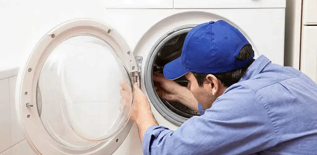 Washing machine repair handyman inspecting a front-load washer drum in Fort Worth, TX