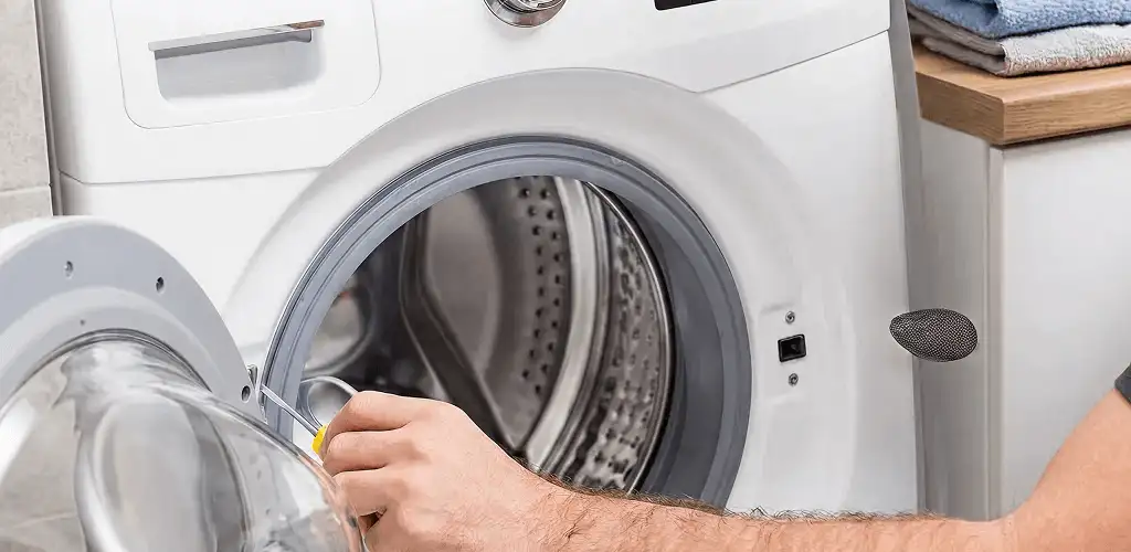 Handyman repairing a front-load washing machine and inspecting the drum in Fort Worth, TX