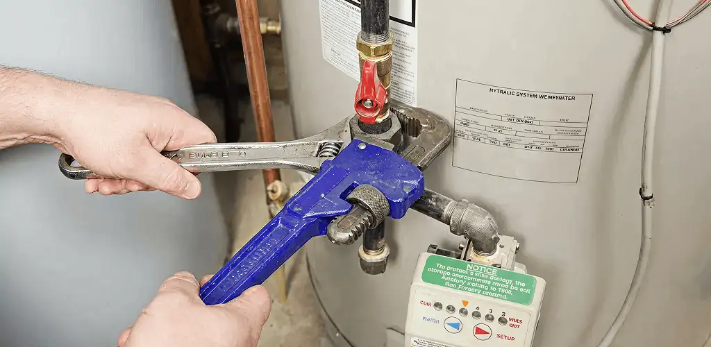 Water heater repair technician tightening the shutoff valve and supply line in Fort Worth, TX